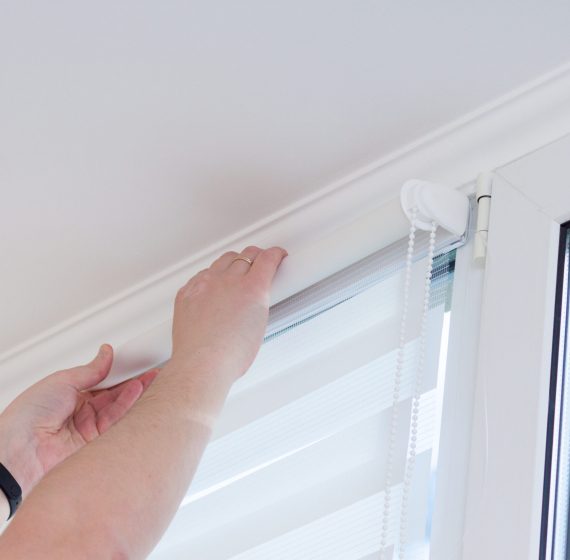 Man hands installing window roller duo system day and night.